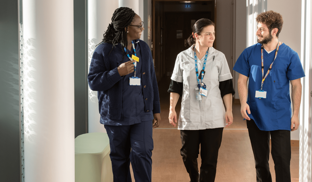 Three members of NHS staff walking down a corridoor in uniform using the Perfect Ward system