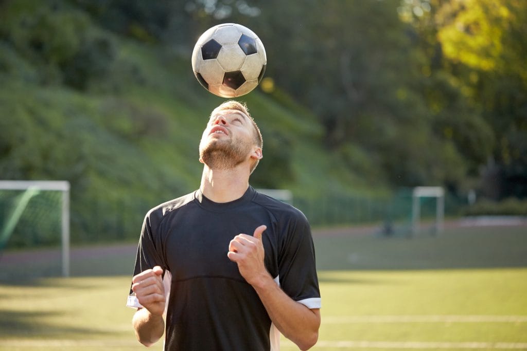 A professional footballer balances a football on his head marking the release of a study into footballers risk of dementia