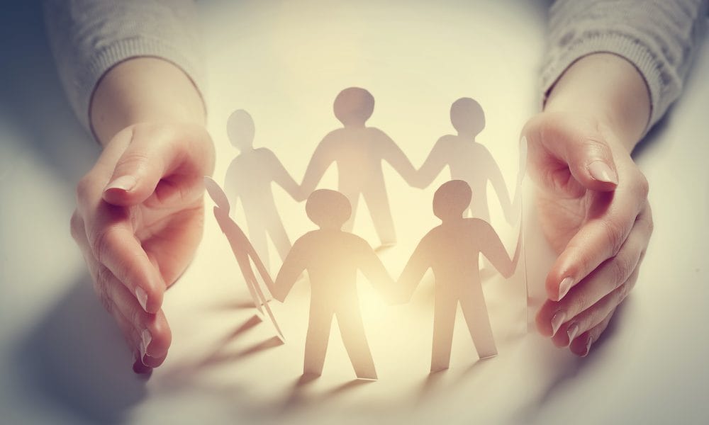 Paper people surrounded by hands in gesture of protection. Concept of insurance Fast-growing AKA maintains commitment to staff and clients