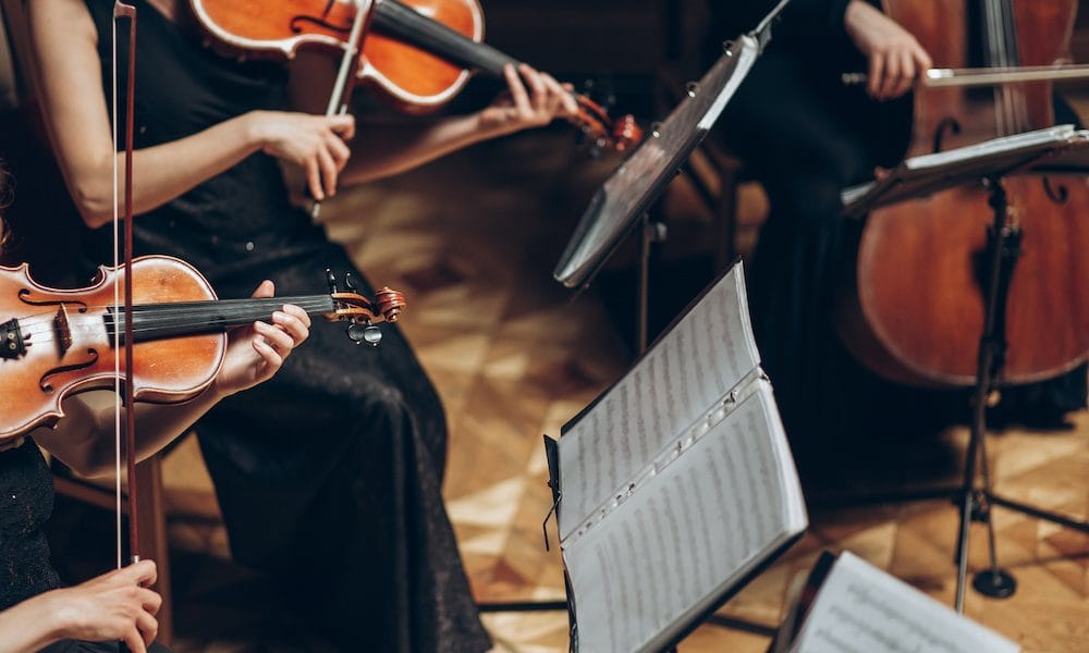 Elegant string quartet playing in luxury room at wedding reception in restaurant. group of people in black performing on violin and cello at theatre orchestra, music concept Classical music and Alzheimer’s – could it improve memory?