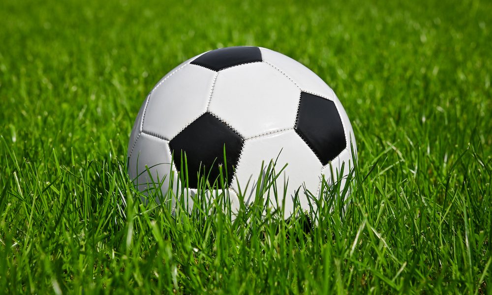 Football ball in green grass of soccer field Fund to support footballers affected by dementia
