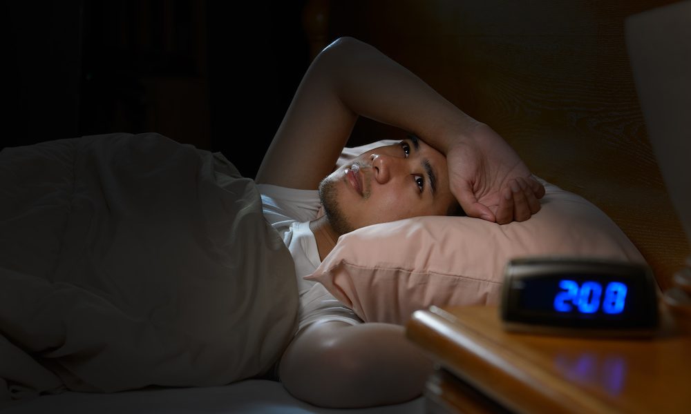 Depressed man suffering from insomnia lying in bed New trauma-related sleep disorder identified