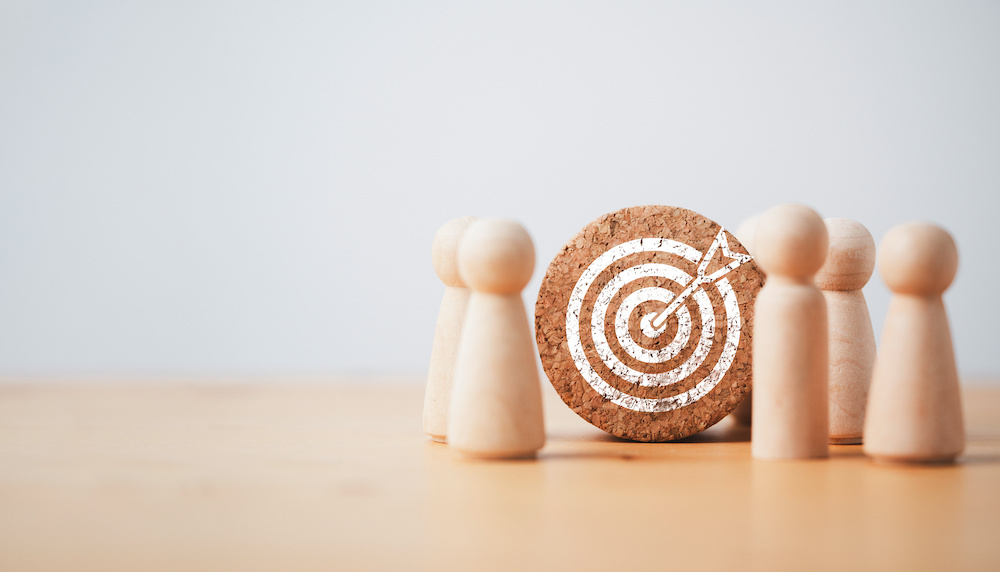 Wooden miniature figures standing with dartboard and arrow for setup business objective target and goal concept. Translating excellence in care into excellence in case management