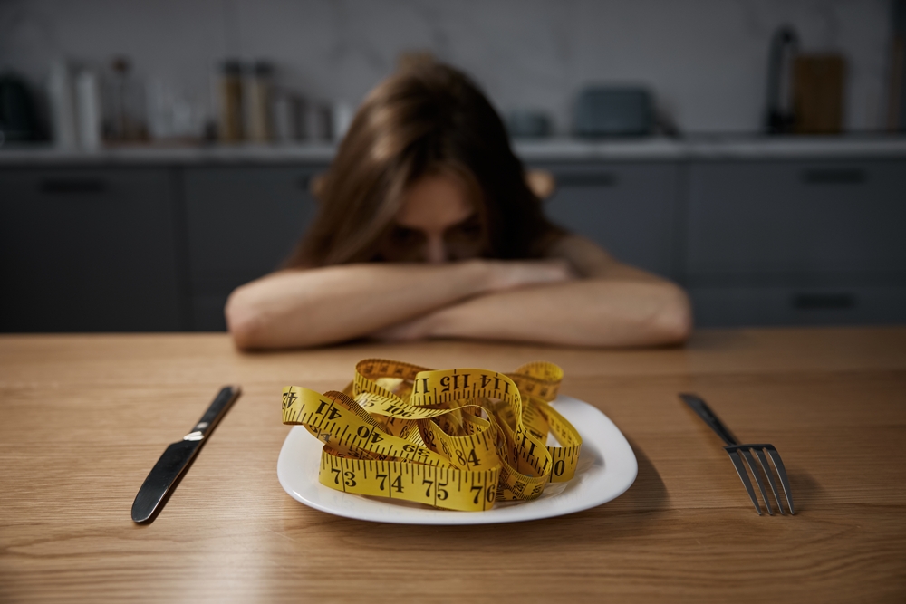 depressed-anorexic-woman-looking-plate-with-measuring-tape-served-dinner Guiding a Loved One Through Eating Disorder Recovery