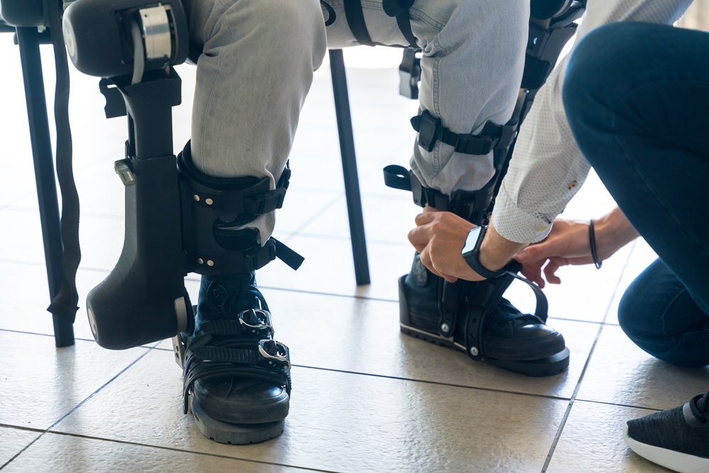 mechanical-exoskeleton-physiotherapist-placing-tapes-legs-disabled-person-place-his-robotic-skeleton-physiotherapy-modern-hospital Exoskeleton linked to improved quality of life in spinal injury study
