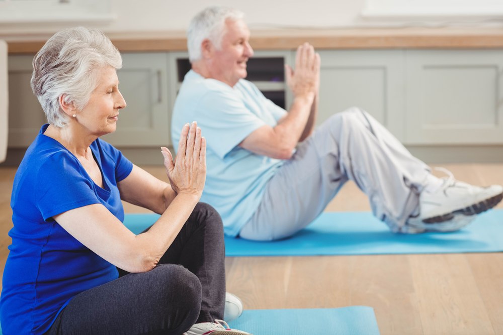 Senior couple performing yoga exercise Exercise linked to slower cognitive and physical decline in Parkinson’s